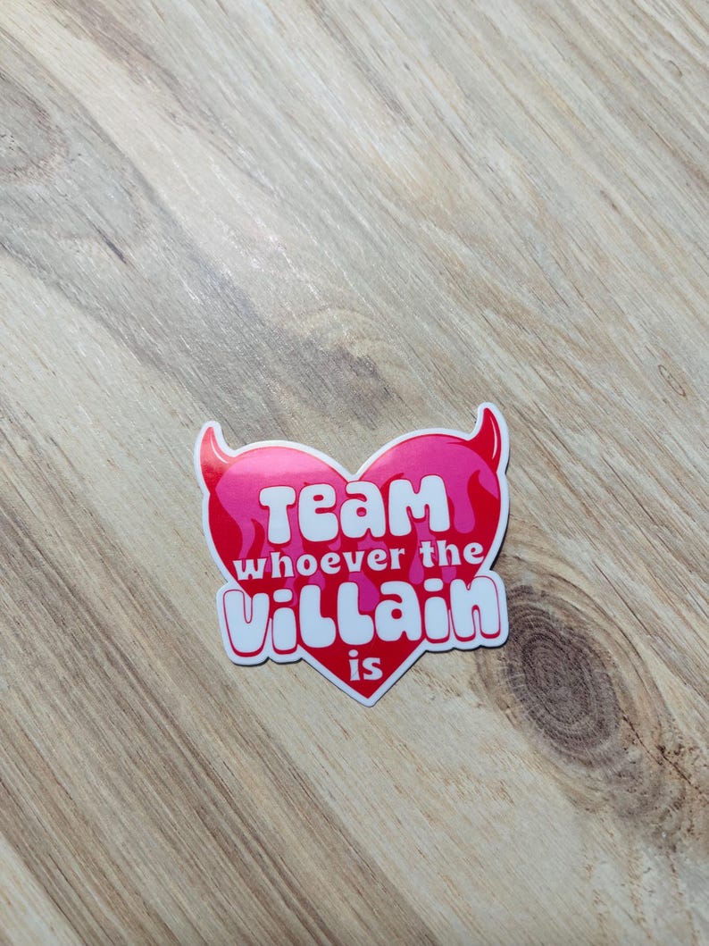 May include: A pink heart-shaped sticker with white text that reads "Team whoever the villain is".