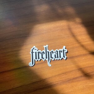 May include: A white sticker with the word "fireheart" written in black gothic lettering.