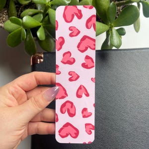 May include: Pink bookmark with a pattern of red hearts.