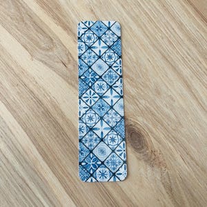 May include: Blue and white patterned bookmark with a geometric design. The bookmark is made of a sturdy material and is perfect for marking your place in a book.