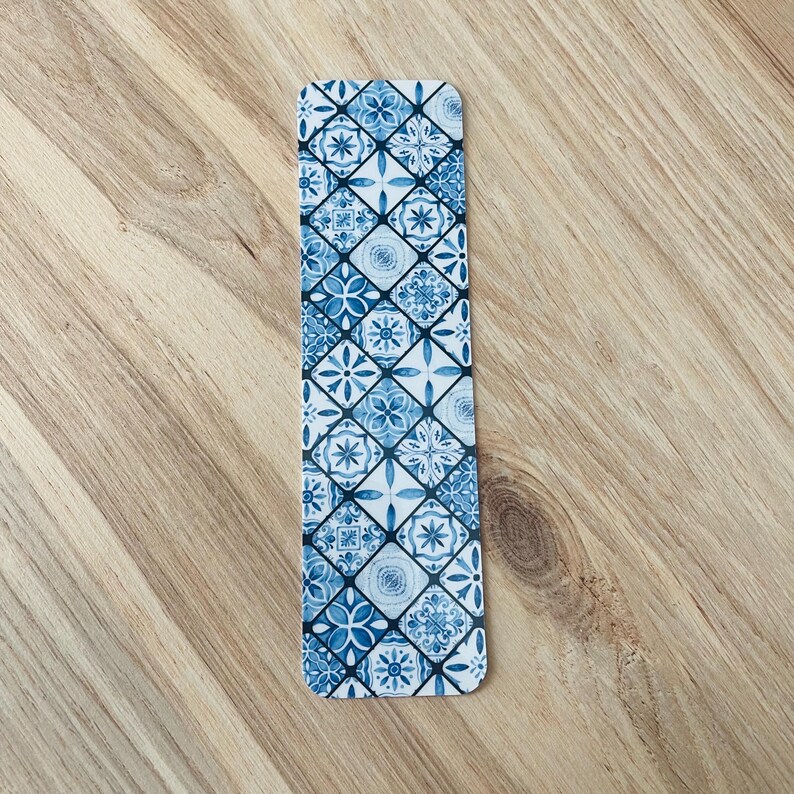 May include: Blue and white patterned bookmark with a geometric design. The bookmark is made of a sturdy material and is perfect for marking your place in a book.