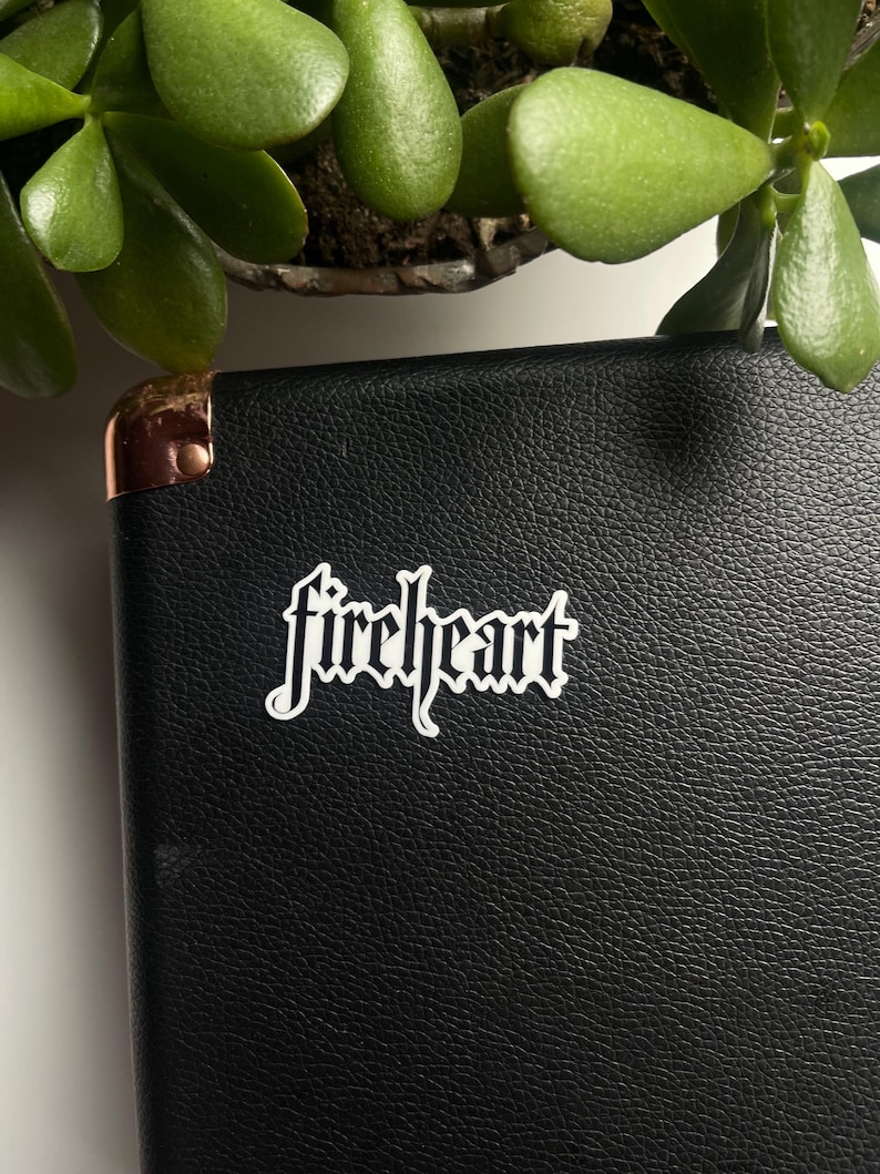 May include: A black leather notebook with a white sticker that says "fireheart" in a gothic font.