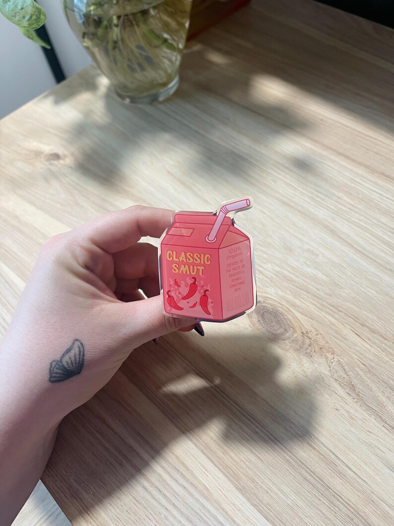 May include: A red and white cartoon illustration of a juice box with a straw. The juice box has the words "CLASSIC SMUT" printed on it and a few red chili peppers around the text.