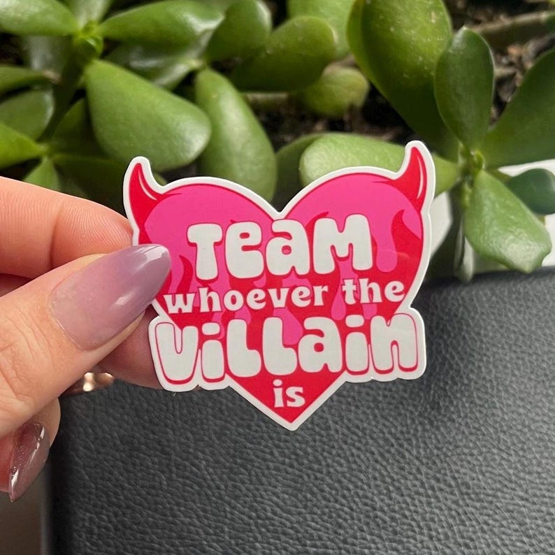 May include: Pink heart-shaped sticker with white text that reads "Team whoever the villain is".