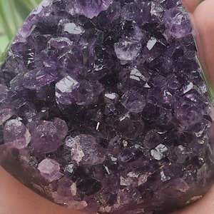 Könnte beinhalten: Ein großer, herzförmiger Amethyst-Kristall-Cluster in tiefem Lila. Der Kristall besteht aus vielen kleineren Kristallen, die zusammen gruppiert sind.