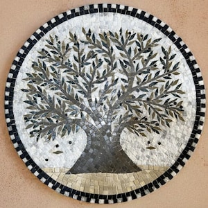 Op de afbeelding: Rond mozaïek kunstwerk met een olijfboom ontwerp. De boom heeft een donkergrijze stam en takken met groene en grijze bladeren. Het mozaïek is omlijst met een zwart-witte rand, tegen een neutrale achtergrond.