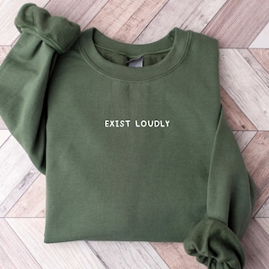 May include: A dark green sweatshirt with the text "EXIST LOUDLY" embroidered in white on the front.