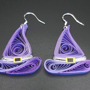 May include: A pair of purple witch hat earrings made of paper quilling. The hats have silver trim and black accents.