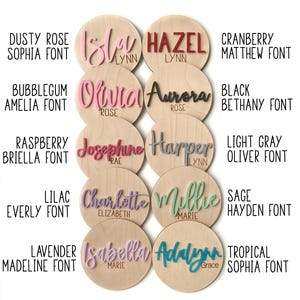 K&ouml;nnte beinhalten: Eine Sammlung personalisierter Namensschilder aus Holz in verschiedenen Farben und Schriftarten. Jedes Schild zeigt einen Namen in einer anderen Farbe, wie Rosa, Rot und Gr&uuml;n, wobei auch der Schriftstil angegeben ist. Der Text enth&auml;lt Namen wie Isla, Hazel und Olivia.