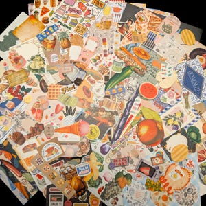 May include: A large collection of assorted paper stickers and die-cut ephemera featuring colorful illustrations of food, fruits, vegetables, drinks, and kitchen-themed motifs, including text labels like "Baking," "Cook," "Gin," and "Eat Laugh."
