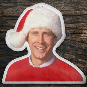 May include: A man wearing a red sweater and a white Santa hat with a red brim. He is smiling with his teeth showing.