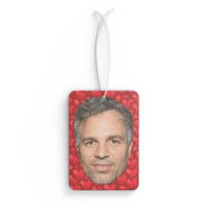 May include: A red car air freshener with a man's face surrounded by red hearts.