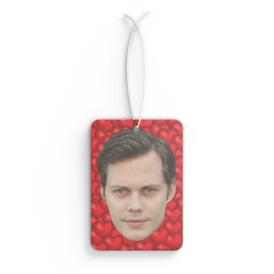 May include: A red car air freshener with a man's face surrounded by red hearts.