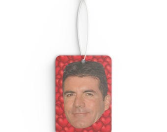 May include: A red car air freshener with a picture of a man's face surrounded by red hearts.