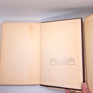 Puede incluir: Libro abierto con p&aacute;ginas envejecidas de color crema. La encuadernaci&oacute;n es marr&oacute;n oscuro. Un sello en la esquina inferior derecha dice "SALT LAKE COUNTY LIBRARY SYSTEM purchased at Public Sale."