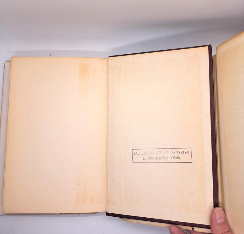 Puede incluir: Libro abierto con p&aacute;ginas envejecidas de color crema. La encuadernaci&oacute;n es marr&oacute;n oscuro. Un sello en la esquina inferior derecha dice "SALT LAKE COUNTY LIBRARY SYSTEM purchased at Public Sale."