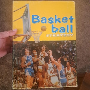 May include: Vintage basketball strategy board game box with a yellow background and the words "Basket ball STRATEGY". The box features a basketball court scene with players in action. The Avalon Hill trademark is also visible.