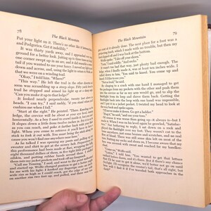 Puede incluir: P&aacute;ginas de libro abiertas con texto. La p&aacute;gina izquierda tiene el t&iacute;tulo "The Black Mountain" y texto sobre un viaje. La p&aacute;gina derecha contin&uacute;a la historia. Las p&aacute;ginas est&aacute;n envejecidas con un tono amarillento.