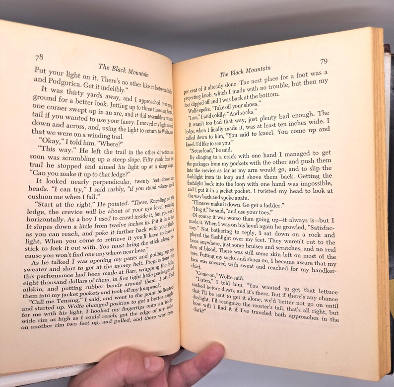 Puede incluir: P&aacute;ginas de libro abiertas con texto. La p&aacute;gina izquierda tiene el t&iacute;tulo "The Black Mountain" y texto sobre un viaje. La p&aacute;gina derecha contin&uacute;a la historia. Las p&aacute;ginas est&aacute;n envejecidas con un tono amarillento.
