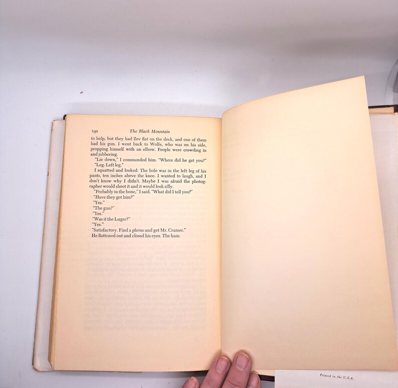 Puede incluir: Un libro abierto con texto en la p&aacute;gina izquierda y una p&aacute;gina derecha en blanco. El texto se titula "The Black Mountain" e incluye di&aacute;logos. Las p&aacute;ginas son de color blanquecino con un lomo marr&oacute;n. Una mano es visible en la parte inferior.