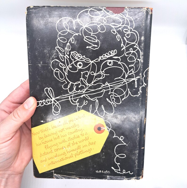 Puede incluir: Una portada de libro vintage con un fondo negro y arte lineal abstracto blanco. Una etiqueta amarilla con texto est&aacute; adjunta a la portada. El texto de la etiqueta dice "Nero Wolfe breaks all precedent..." y contin&uacute;a con una descripci&oacute;n de la trama del libro.