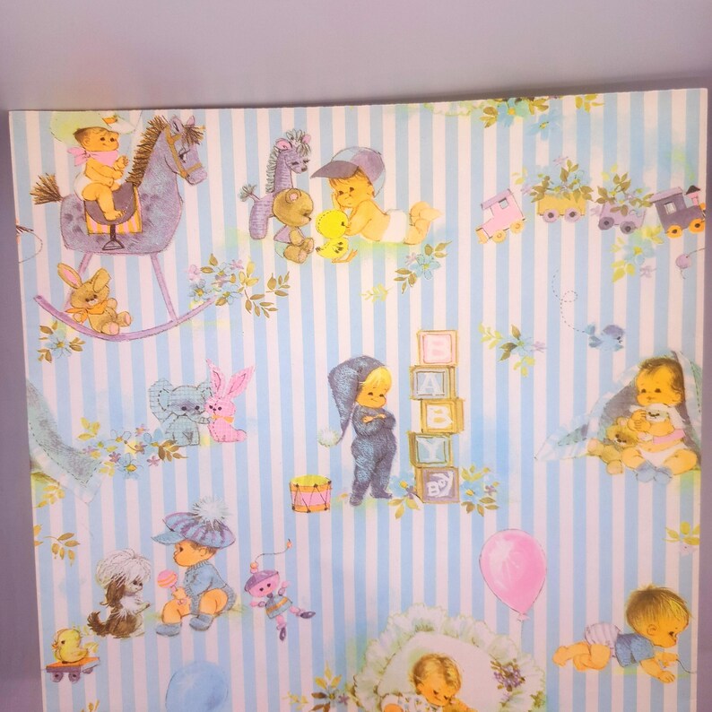 May include: A light blue and white striped wallpaper featuring a repeating pattern of illustrations including babies, a rocking horse, a toy train, alphabet blocks spelling BABY, a pink balloon, and various small animals like rabbits and dogs.