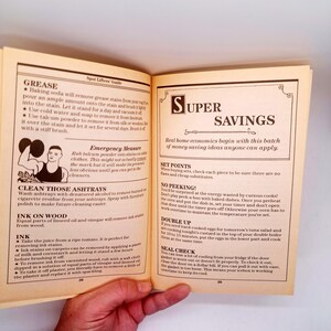 May include: Open book pages with text on stain removal and home economics tips. The left page details grease stain removal with baking soda and talcum powder. The right page has the title "SUPER SAVINGS" and tips on set points and no peeking.