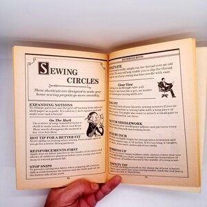 May include: Open book with sewing tips. The left page has the title "Sewing Circles" and tips on expanding notions and reinforcing garments. The right page has tips on threading needles and using rulers. The pages are yellowed.