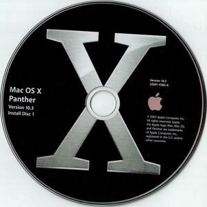 May include: A black CD-ROM with the text "Mac OS X Panther Version 10.3 Install Disc 1" and a large silver "X" in the center. The Apple logo is visible, along with copyright information.