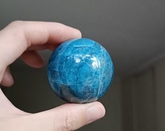 May include: A blue and white sphere made of polished aquamarine crystal. The sphere is smooth and has a swirling pattern.