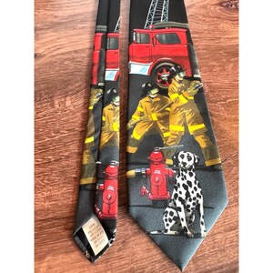 May include: A black polyester tie featuring a repeating pattern of red fire trucks, firefighters in yellow gear, and a Dalmatian dog. The tie also includes red fire hydrants. Made in the USA.