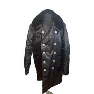May include: Black satin coat with a faux fur collar and silver-colored buttons. The double-breasted coat has a military-style design. The coat is a long length and has a tailored fit.
