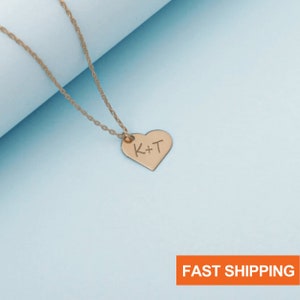 May include: A gold heart-shaped pendant necklace with the initials "K+T" engraved on it.