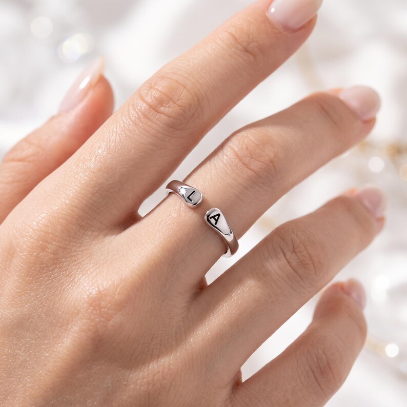 A breathtakingly elegant adjustable initial ring designed to combine modern versatility with deeply personalized meaning. This stunning 925 sterling silver piece features a sleek, open-cuff design with your choice of two custom-engraved letters on each resting end. Whether you are keeping a loved one's initial close to your own, representing your children, or looking for the perfect everyday signature piece, this wrap ring is the ultimate bespoke accessory.