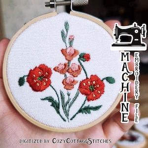 Puede incluir: Archivo de bordado a máquina de un diseño floral con flores rojas y rosas y hojas verdes. El diseño está bordado en tela blanca en un aro de bordado redondo. El texto "MACHINE EMBROIDERY FILE" es visible en el lado derecho de la imagen. El texto "DIGITIZED BY COZYCOTTAGE STITCHES" es visible en la parte inferior de la imagen.