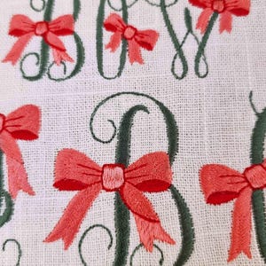 May include: Embroidered design of the word "BOY" with a green outline and pink bows. The text "DIGITIZED BY COZYCOTTAGE STITCHES" is at the bottom of the image.