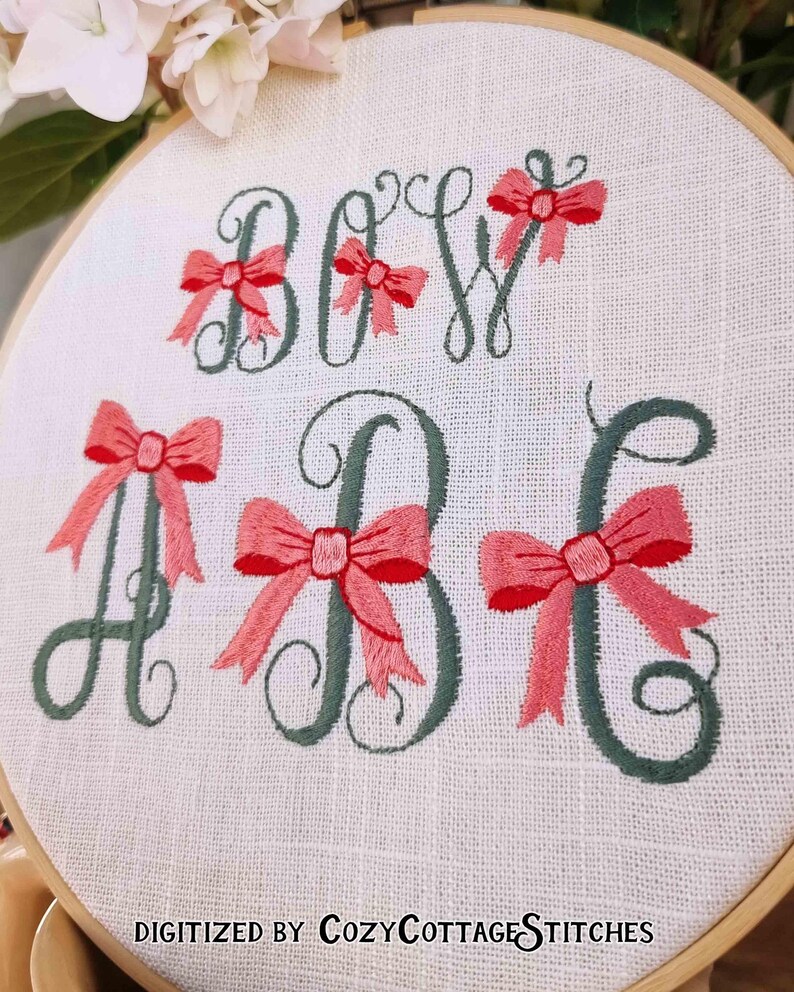 May include: Embroidered hoop art with the letters "Baby" in green cursive with pink bows. The text "Digitized by Cozy Cottage Stitches" is at the bottom of the hoop.