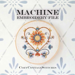May include: A machine embroidery file displayed in a wooden hoop. The design features a central flower with orange, yellow, and blue petals, surrounded by a heart-shaped frame. The text "MACHINE EMBROIDERY FILE" and "Cozy Cottage Stitches" are visible.