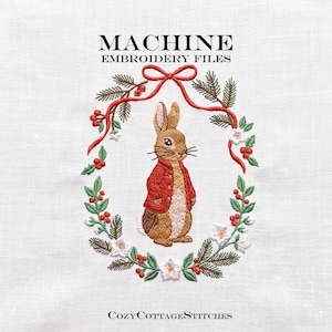 Può includere: Disegno per ricamo a macchina con un coniglio marrone che indossa una giacca rossa, centrato in una ghirlanda di rami di pino verdi, bacche rosse e fiori bianchi, legata con un nastro rosso. Testo: MACHINE EMBROIDERY FILES e COZYCOTTAGESTITCHES.
