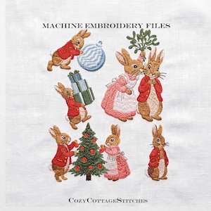 May include: Machine embroidery files featuring brown rabbits in red jackets and pink dresses with Christmas elements like a tree, ornaments, and gifts. The text reads MACHINE EMBROIDERY FILES and CozyCottageStitches on a white fabric background.