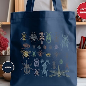 May include: A navy blue tote bag with a colorful insect design. The bag has a white label that says "NAVY".