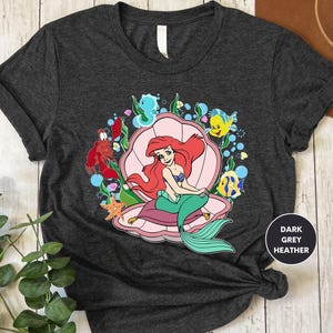 a t - shirt with a mermaid sitting on top of it