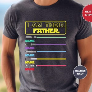 a t - shirt that says i am the father next to a pair of jeans