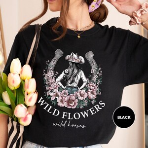 a woman wearing a black wild flowers t - shirt
