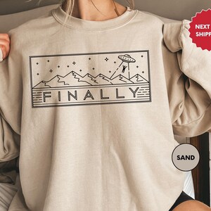 a woman wearing a sweatshirt with the word finaly printed on it