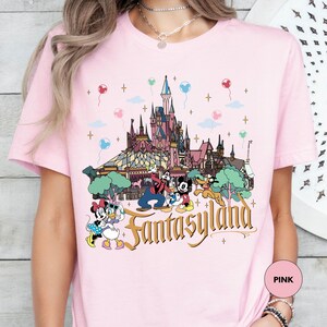 a woman wearing a pink disneyland shirt