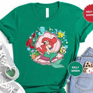 a green shirt with an image of a little mermaid on it