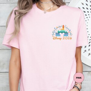 A woman wearing a pink t-shirt with a Disney logo and text on it.