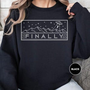 a woman wearing a black sweatshirt with the word finally printed on it