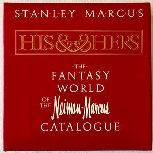 May include: A square, red hardcover book titled Stanley Marcus His & Hers The Fantasy World of the Neiman-Marcus Catalogue. The cover features white and gold text with a central rectangular border enclosing the title in gold lettering.